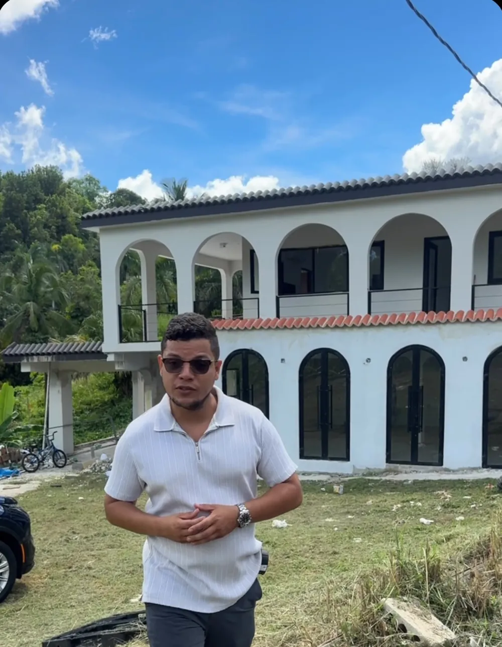 Yulian Vazquez frente a una casa de dos niveles con arcos